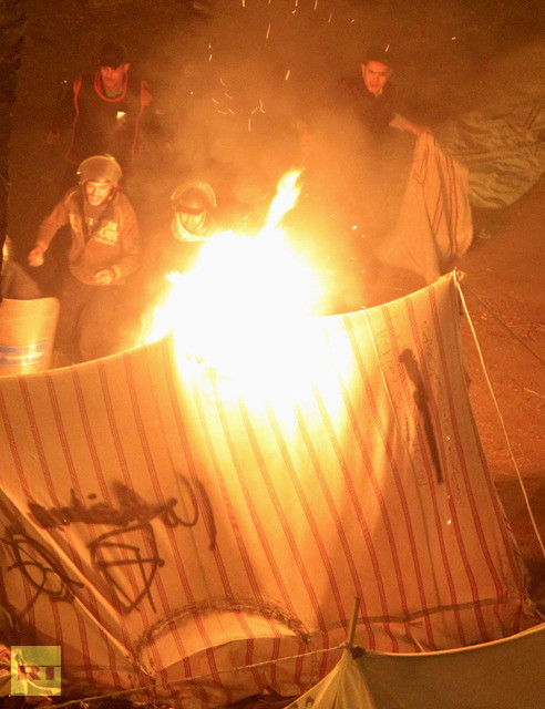 Cảnh sát phun lửa đốt cháy lều của những người biểu tình để giải tán đám đông.