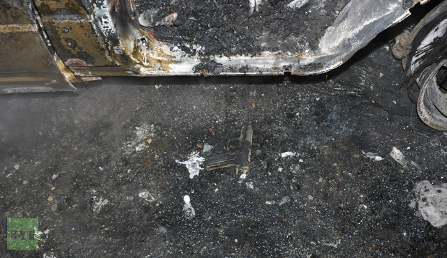 Một khẩu súng ngắn nằm bên cạnh cửa chiếc xe bốc cháy.