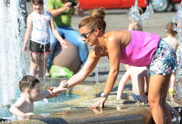 Cậu nhóc Kai được mẹ cho phép đùa nghịch dưới vòi phun nước tại quảng trường thành phố Krakow, Ba Lan.