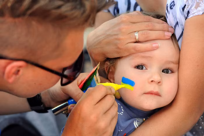 Một em bé Ukraina khác đang được vẽ cờ lên má. Một em bé Ukraina khác đang được vẽ cờ lên má.