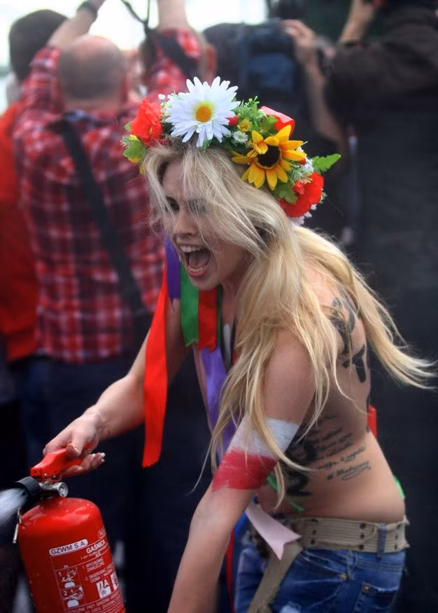 Người đẹp ngực trần dùng bình cứu hỏa xịt ngay trước sân vận động diễn ra lễ khai mạc EURO 2012 ở Warsaw, Ba Lan