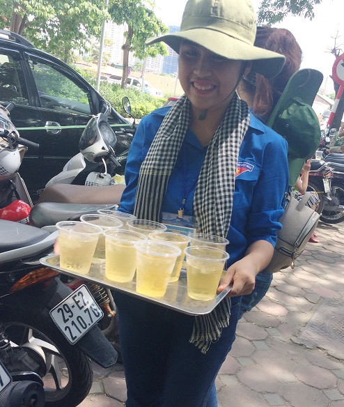 Dưới nắng nóng, các bạn sinh viên tình nguyện vẫn nhiệt tình bê nước tới mời từng bác phụ huynh trong thời gian chờ con thi. (Ảnh: Ngọc Bích)