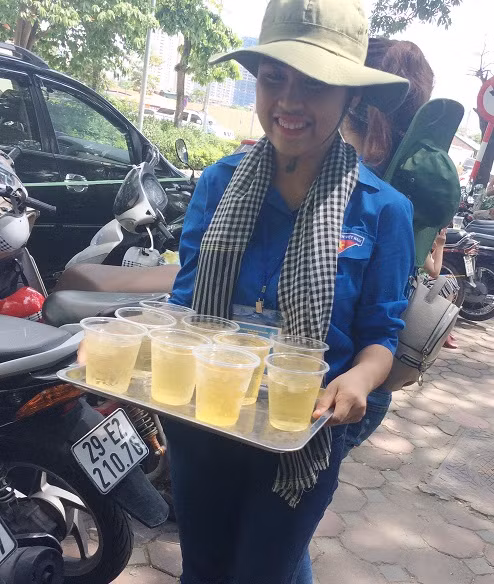 Dưới nắng nóng, các bạn sinh viên tình nguyện vẫn nhiệt tình bê nước tới mời từng bác phụ huynh trong thời gian chờ con thi. (Ảnh: Ngọc Bích)