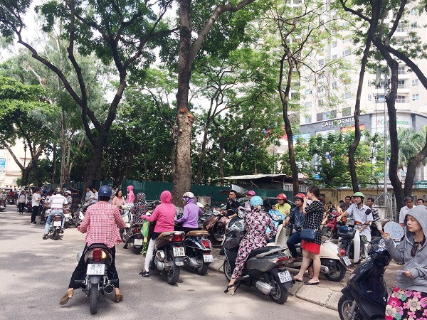 Hình ảnh các vị phụ huynh xếp hàng dài ngoài đường chờ con em mình dưới cái nắng oi bức, cùng vẻ mặt lo lắng, căng thẳng (Ảnh: Ngọc Bích)