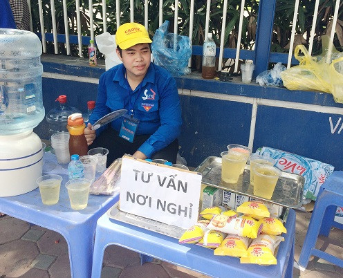 Hình ảnh một bạn thanh niên ướt đãm mồ hôi, ngồi ở bàn tư vấn để phục vụ miễn phí cho mọi người như đồ ăn, nước uống giải khát, tư vấn nơi nghỉ ngơi. (Ảnh: Ngọc Bích)