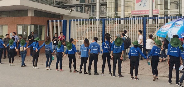 Do điểm thi gần đường giao thông lớn, nhiều xe qua lại, để đảm bảo an toàn cho các em thí sinh và phụ huynh. Các bạn thanh niên tình nguyện đã cầm tay nhau xếp thành hàng dài nhằm phân cách giữa đường đi và cổng trường nơi các em ra vào. (Ảnh: Ngọc Bích)