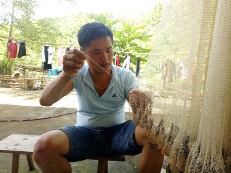 Sau những lần đánh cá, thầy Tuất lại thực hiện công đoạn thủ công khâu vá chiếc chài bị hư hỏng. Ảnh: Hữu Chí.