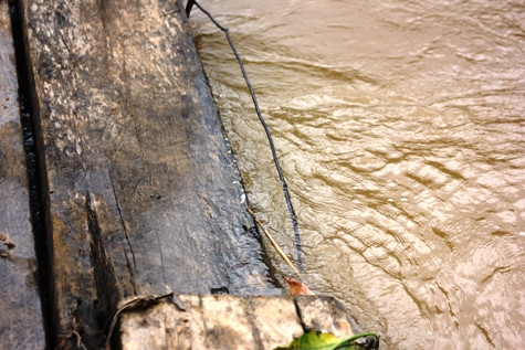 Mỗi khi có mưa lũ, nước suối dâng cao tới mặt cầu, đe dọa tính mạng của học sinh bản Vịn. Ảnh: Xuân Quang.