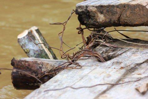 Cây cầu tạm bắc qua suối được ghép bằng những mảnh ván, chằng néo sơ sài. Ảnh: Xuân Quang.
