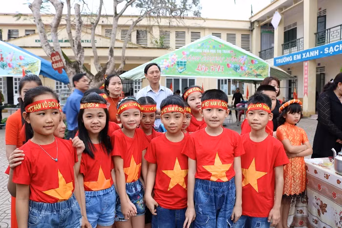 Các em học sinh không ai bảo ai đều đồng phục áo đỏ, thắt băng đỏ với hàng chữ vàng nổi bật: “Tôi yêu Việt Nam. Việt Nam vô địch”.