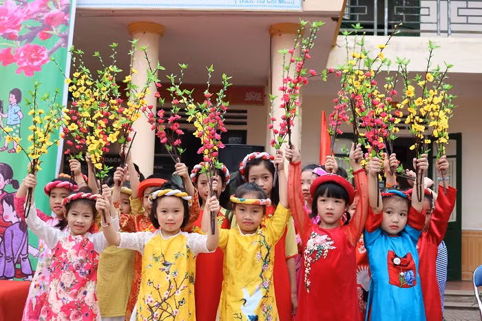 Một số em học sinh trong trang phục áo dài truyền thống, mang hoa để cổ vũ U23 Việt Nam.