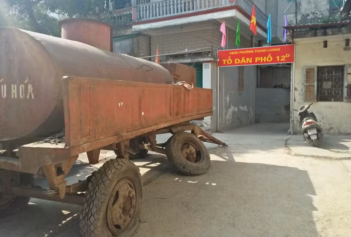 Một chiếc xe rơ – mooc đổ xiêu, đổ vẹo, hoen gỉ hết hạn sử dụng nằm chắn ngay ở lối ra vào tổ dân phố gây ách tắc giao thông, thậm chí có thể gây nguy hiểm tính mạng đối với người đi đường. Ảnh: Thụy Du.