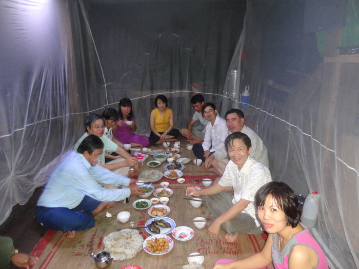 Nhà khoa học Vương Xuân Tình (thứ hai, hàng bên phải) dùng bữa tối cùng đồng nghiệp và cán bộ Vườn Quốc gia Cát Tiên (tỉnh Đồng Nai). Mâm cơm phải đặt trong chiếc màn lớn để chống muỗi (năm 2016). Ảnh: NVCC Bữa cơm tối trong ngày làm việc ở Vườn quốc gia Cát Tiên (thuộc tỉnh Đồng Nai), 2016. Ăn cơm trong mùng để chống muỗi. Tác giả là người thứ hai, bên phải..JPG