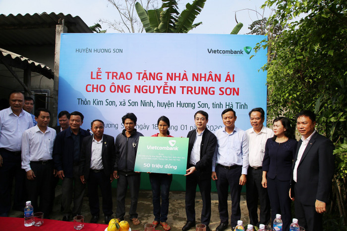 Ông Nghiêm Xuân Thành – Bí thư Đảng ủy, Chủ tịch Hội đồng quản trị Vietcombank (thứ 5 từ phải sang) trao số tiền ủng hộ của Vietcombank để xây nhà nhân ái cho hộ gia đình ông Nguyễn Trung Sơn tại thôn Kim Sơn, xã Sơn Ninh.