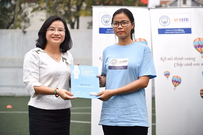 Bà Ngô Thu Hà – Phó Tổng giám đốc Ngân hàng SHB trao tặng chứng nhận hoàn thành khóa học cho các học viên. “Chúng tôi hoàn toàn ủng hộ những đóng góp tích cực của Manchester City cho các thanh thiếu niên Việt Nam và sẵn sàng đồng hành cùng MCFC trong hoạt động cộng khác của MCFC tại Việt Nam không chỉ ở các làng trẻ SOS mà nhân rộng hơn nữa trong cộng đồng”, bà Ngô Thu Hà khẳng định. Bà Ngô Thu Hà – Phó Tổng giám đốc Ngân hàng SHB trao tặng chứng nhận hoàn thành khóa học cho các học viên. “Chúng tôi hoàn toàn ủng hộ những đóng góp tích cực của Manchester City cho các thanh thiếu niên Việt Nam và sẵn sàng đồng hành cùng MCFC trong hoạt động cộng khác của MCFC tại Việt Nam không chỉ ở các làng trẻ SOS mà nhân rộng hơn nữa trong cộng đồng”, bà Ngô Thu Hà khẳng định.