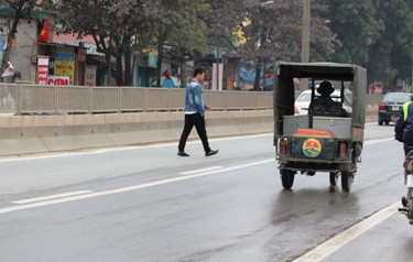 Một thanh niên thản nhiên đi bộ giữa lòng đường Phạm Văn Đồng bất chấp nguy hiểm (ảnh: THỤY DU).