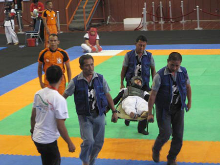 Một VĐV rời thảm đấu bằng cáng.