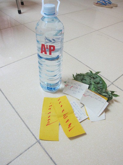 Chai nước, lá cây và tờ giấy mà “thần y” dùng để chữa bệnh. (Ảnh chụp qua ĐTDĐ)