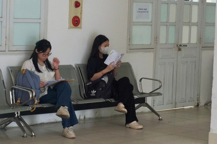 Trong thời gian chờ vào phòng làm thủ tục dự thi, thí sinh Vũ Thái Hà Linh (áo trắng) cùng bạn tranh thủ ôn tập. Ảnh: Đào Hiền Trong thời gian chờ vào phòng làm thủ tục dự thi, thí sinh Vũ Thái Hà Linh (áo trắng) cùng bạn tranh thủ ôn tập. Ảnh: Đào Hiền