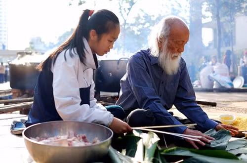 Những người thầy vĩ đại luôn biết cách truyền cảm hứng cho học trò. Trong ảnh là PGS.Văn Như Cương ở tuổi 80 vẫn tận tình dạy học trò cách gói bánh chưng. ảnh: Văn Thùy Dương.