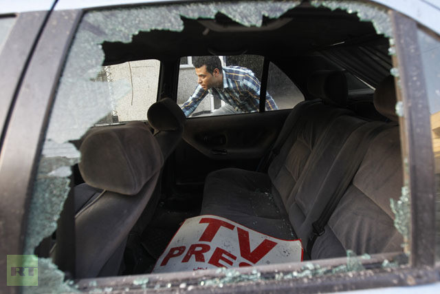 Một nhà báo người Palestine đứng gần xe hơi của mình sau vụ không kích trụ sở làm việc.