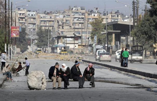 Những người đàn ông ngồi trên chiếc cột điện đổ ngang đường phố ở Aleppo, Syria ngày 16/12.