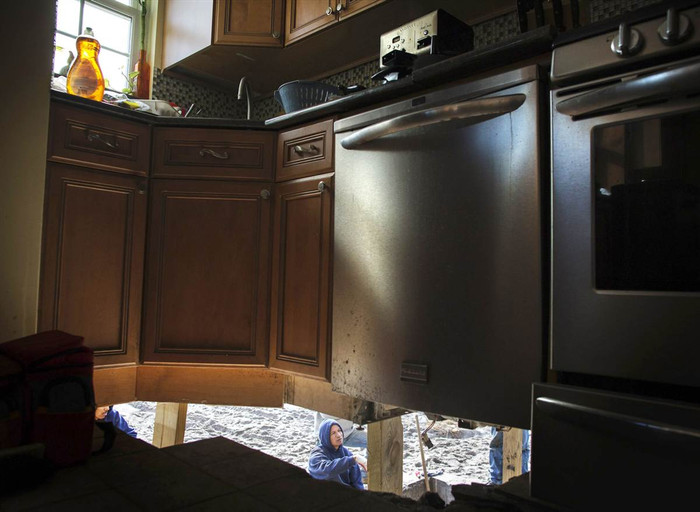 Một công nhân xây dựng đứng bên dưới chiếc lỗ được tạo ra bởi bão Sandy tại Belle Harbor, New York hôm 14/11. Một công nhân xây dựng đứng bên dưới chiếc lỗ được tạo ra bởi bão Sandy tại Belle Harbor, New York hôm 14/11.