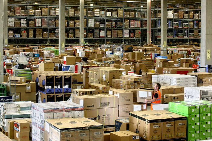 TV Plasma, xe đạp tập thể dục, đồ chơi được xếp chồng lên nhau trong trung tâm phân phối Swansea của Amazon. TV Plasma, xe đạp tập thể dục, đồ chơi được xếp chồng lên nhau trong trung tâm phân phối Swansea của Amazon.