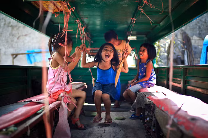Trẻ em vui chơi trong một chiếc xe cũ tại Cebu, Philippines. Ảnh Mac Kwan.