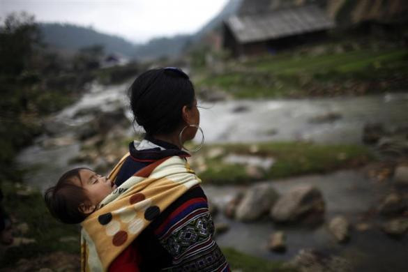 Một bà mẹ H'mong địu con đi dọc bờ suối tại thị trấn Sapa ngày 24/5/2011