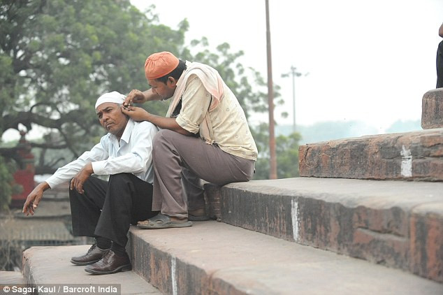 Mohhamed Abbas lấy ráy tai cho một khách hàng trên phố. Mohhamed Abbas lấy ráy tai cho một khách hàng trên phố.