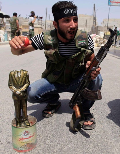 Một phiến quân hò hét bên cạnh bức tượng cựu Tổng thống Syria Hafez al-Assad, cha của đương kim Tổng thống Bashar al Assad.