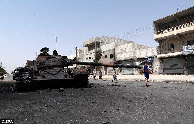 Trẻ em Syria chơi bên cạnh đống đổ nát của một chiếc xe tăng của quân chính phủ.