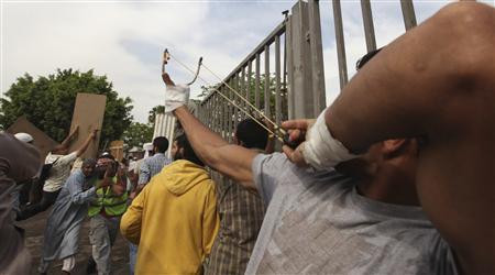 Người biểu tình bắn đá về phía các nhân viên an ninh trước cổng Bộ Quốc phòng. Ảnh Reuters