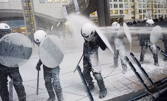 Cảnh sát cố gắng chống chọi với vòi sữa được phun từ những nông dân biểu tình đề nghị trợ cấp giá sữa đang ngày càng sụt giảm bên ngoài Nghị viện châu Âu tại Brussels ngày 26/11. Cảnh sát cố gắng chống chọi với vòi sữa được phun từ những nông dân biểu tình đề nghị trợ cấp giá sữa đang ngày càng sụt giảm bên ngoài Nghị viện châu Âu tại Brussels ngày 26/11.