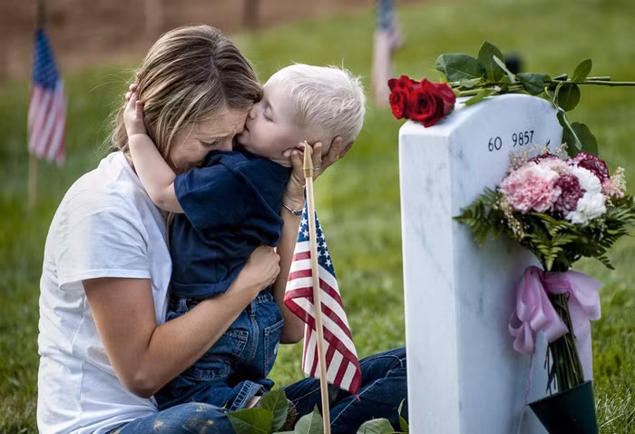 Brittany Jacobs và cậu con trai 17 tháng tuổi Christian ôm nhau trước mộ của người chồng Christopher Jacobs tại nghĩa trang Arlington National Cemetery ở Arlington, Virginia, Mỹ trong "Ngày tưởng niệm".