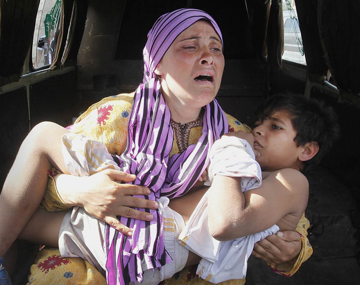 Bà mẹ Syria bế đứa con trai 5 tuổi bị bắn bởi các nhân viên kiểm soát an ninh biên giới nước này khi họ đang cố gắng vượt sông sang Li-băng để chạy trốn bạo lực.