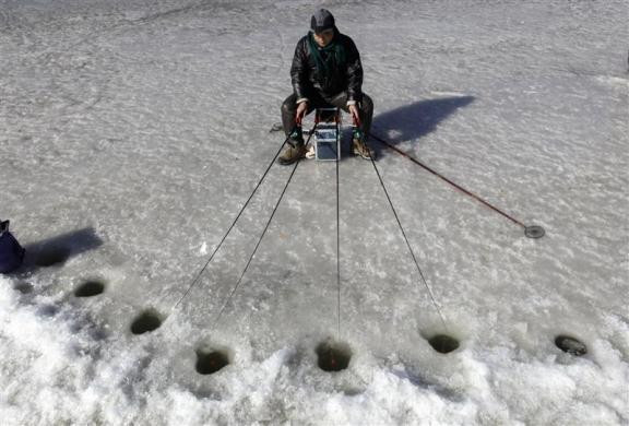 Một người đàn ông thi câu cá trên hồ băng ở Bắc Kinh, Trung Quốc ngày 31/1/2010.