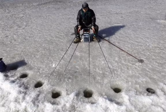 Một người đàn ông thi câu cá trên hồ băng ở Bắc Kinh, Trung Quốc ngày 31/1/2010.