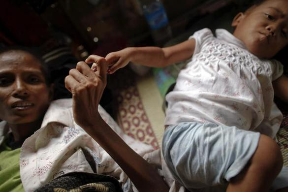 Ma Jam, 42 tuổi, nhiễm AIDS nắm tay bé Kanama (2 tuổi) nhiễm HIV tại nhà tế bần ở ngoại ô thành phố Yangon, Myanmar ngày 26/5/2012.