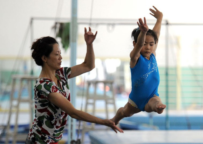 Huấn luyện viên giúp một bé gái tập luyện tại trung tâm thể thao ở Nam Kinh. Huấn luyện viên giúp một bé gái tập luyện tại trung tâm thể thao ở Nam Kinh.