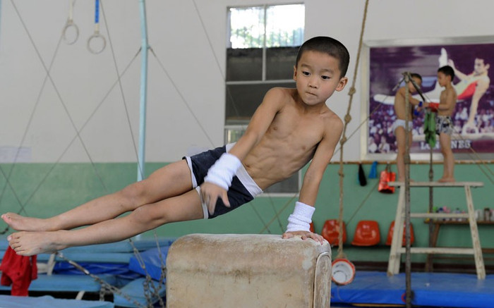 Trẻ em thuộc đội thể dục dụng cụ trong giờ tập luyện tại trung tâm huấn luyện thể thao ở Nam Kinh. Trẻ em thuộc đội thể dục dụng cụ trong giờ tập luyện tại trung tâm huấn luyện thể thao ở Nam Kinh.