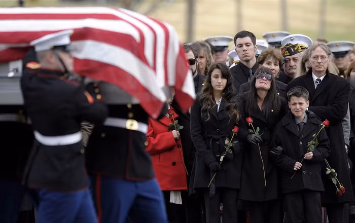 Catherine Stouffer cùng hai người con Shannon (17 tuổi) và Shane (12 tuổi) đi bên cạnh linh cữu của chồng - một cựu sĩ quan Hải quân - trên đường tới nghĩa trang tại Arlington Cemetery ở Arlington (Mỹ) ngày 7/12. Anh Gary Stouffer (37 tuổi) bị giết hại trong một cuộc diễu hành tại Midland, Texas, vào ngày 15/11.