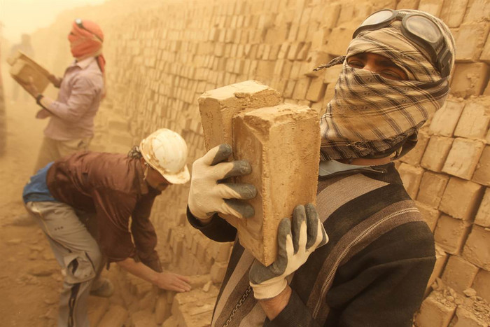 Các công nhân Iraq đang xếp những viên gạch vừa được sấy khô trong cơn bão cát tại Maysan, cách Baghdad 250 dặm về phía nam ngày 18/3.