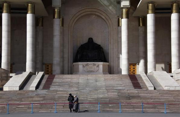 Một người đàn ông mặc trang phục truyền thống của Mông Cổ đứng nói chuyện với nhân viên bảo vệ phía trước bức tượng Thành Cát Tư Hãn của tòa nhà Quốc hội tại Ulaanbaatar ngày 3/4/2012.