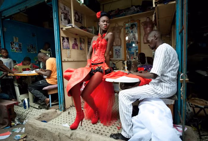 Một người mẫu đứng trước gian hàng may mặc ở trung tâm Dakar, Senegal trong tuần lễ thời trang Dakar. Cô mặc chiếc váy của nhà thiết kế người Senegal sống tại Mỹ Yolande Ngom Mancini. Ảnh: Vincent Boisot.