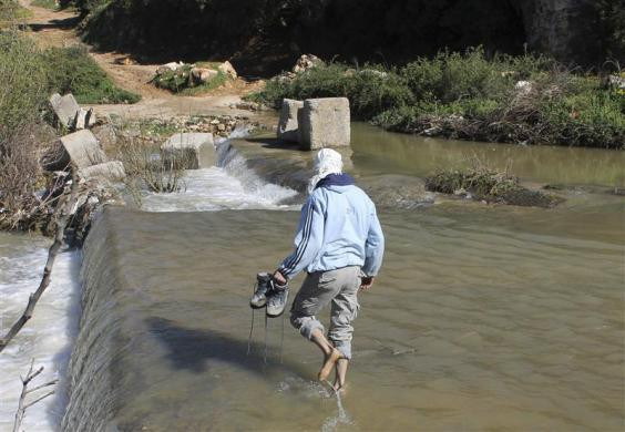Một người đàn ông Syria vượt qua sông để tới làng Wadi Khaled ở miền bắc Lebanon ngày 18/3/2012.