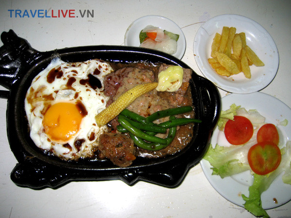 35. Bò bít tết: Thịt bò xắt miếng to và dày, sau đó đem áp chảo cho chín tái rồi tưới thêm gia vị. Món này dùng với tương ớt, xì dầu hoặc nước sốt đặc biệt, với vài miếng xà lách, cà chua, chưa leo...Ăn đâu: Bò Bít Tết Hoả Diệm Sơn – 331 Nguyễn Trãi, Q.1, TP.HCM ... 35. Bò bít tết: Thịt bò xắt miếng to và dày, sau đó đem áp chảo cho chín tái rồi tưới thêm gia vị. Món này dùng với tương ớt, xì dầu hoặc nước sốt đặc biệt, với vài miếng xà lách, cà chua, chưa leo...Ăn đâu: Bò Bít Tết Hoả Diệm Sơn – 331 Nguyễn Trãi, Q.1, TP.HCM ...