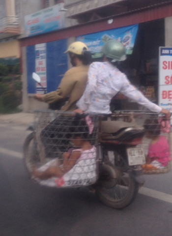 Chở 2 đứa bé trong rọ sắt. Ảnh: Nguyen Thi Thanh Xuan
