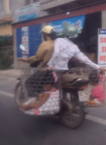Chở 2 đứa bé trong rọ sắt. Ảnh: Nguyen Thi Thanh Xuan